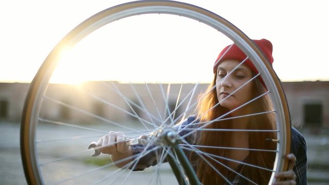 Young woman installing bicycle wheel