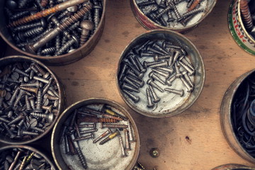 Filtered screws and bolts in tin can on wooden background