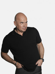 Fototapeta premium Suspicious middle aged man with hands in pockets looking away on white background