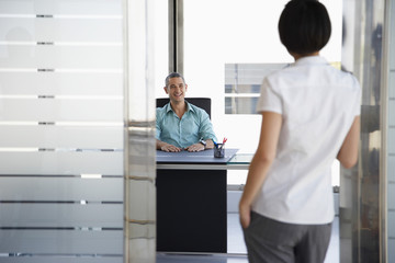 Fototapeta premium Smiling young man talking to woman standing in doorway at his office