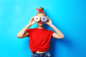 Obraz premium Young beautiful woman with doughnuts on blue background
