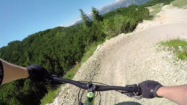 FPV: Extreme biker riding downhill along the rocky flow track in bike park