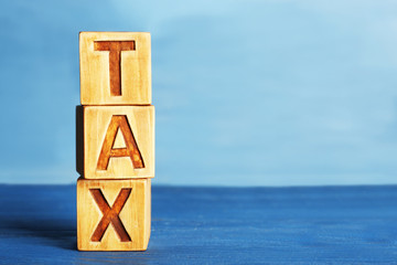 Cubes with word TAX on wooden surface