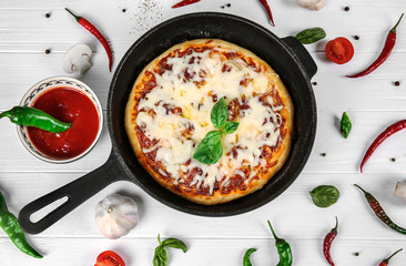Freshly baked pizza in a pan on wooden background