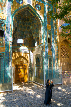 Young Iranian girl in chador taking picture in front of Jameh Mosque, Natanz, Iran