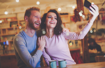 Beautiful couple taking selfie in cafe
