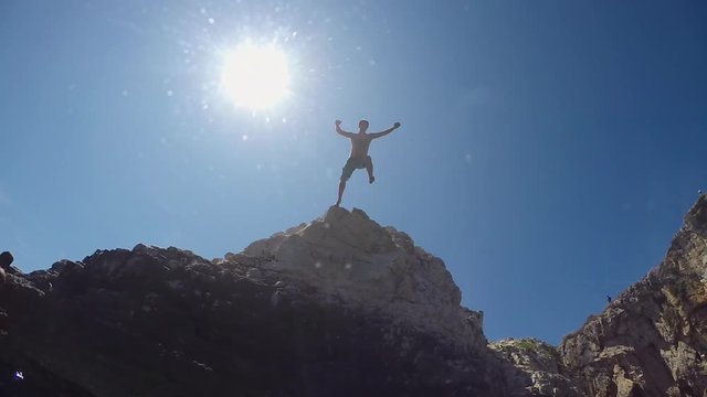 SLOW MOTION CLOSE UP UNDERWATER: Man jumping off a high ocean cliff into water 