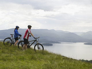Side view of a couple with bicycles near the peaceful lake