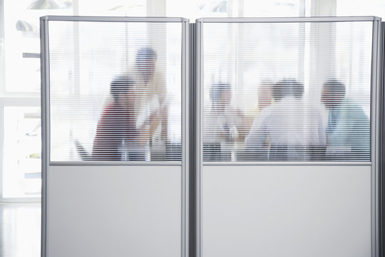 Group Of Business People In Meeting Behind Translucent Wall In Office