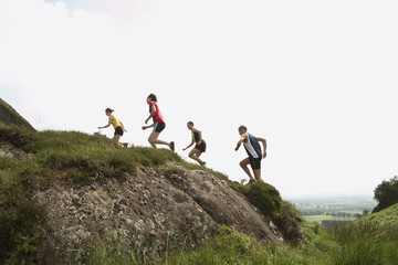 Side view of a group of people running on hill