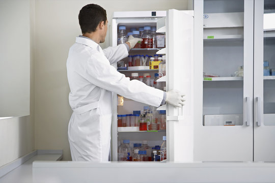 Male scientist selecting bottle from refrigerator in laboratory