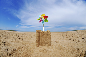 Fototapeta na wymiar Sand castle with pinwheel on beach
