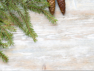 Christmas fir tree branches with cones on rustic wooden board wi