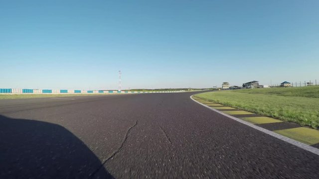 FPV LOW ANGLE: Racecar driving fast competing on racetrack on sunny day