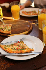 Plate with tasty pizza and glasses of juice on wooden table, close up view