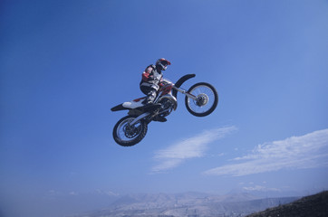Fototapeta na wymiar Low angle view of a man on mountain bike jumping against blue sky