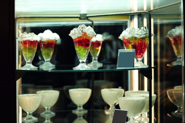 Glass stand with tasty sweets in cafe, close up view