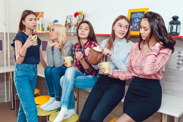 Obraz premium Beautiful girls standing in kitchen at the hostel talking and drinking tea.