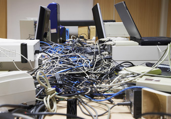 Closeup side view of messed wires connecting computers and printers in office