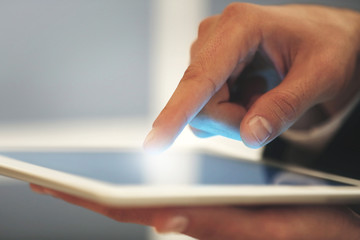 Male finger touching tablet screen on blurred background