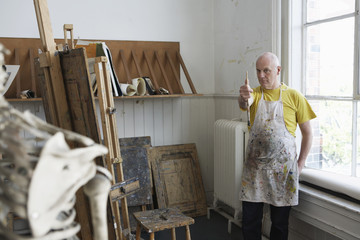 Middle aged male artist studying skeleton in studio