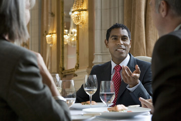 Mixed race businessman in discussion with colleagues at restaurant table