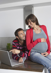 Fototapeta premium Happy young pregnant woman with man doing online shopping
