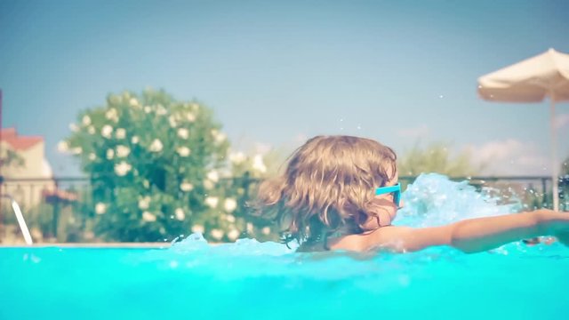 Happy child playing in swimming pool. Girl having fun outdoors. Summer vacation and holiday concept. Slow motion