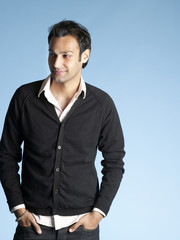 Fototapeta premium Portrait of handsome young man with hands in pockets standing isolated on blue background