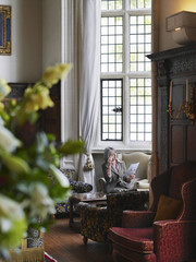Middle aged woman sitting on antique furniture and reading
