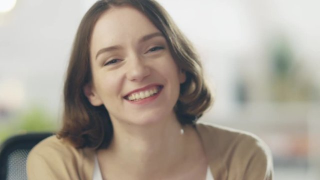 Beautiful Young Woman Laughs on the Camera. Her Background is Bright and Blurred.  Shot on RED Cinema Camera in 4K (UHD).