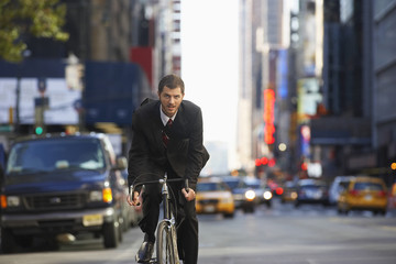 Portrait of young businessman riding bicycle to work on urban street