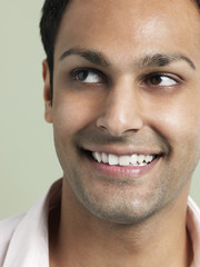 Obraz premium Closeup of young Asian man looking away and smiling on colored background