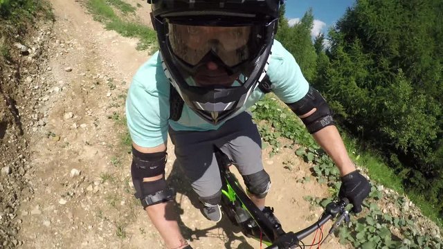 PORTRAIT CLOSE UP: Young pro downhill mountain biker riding dirt flow trail