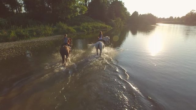 CLOSE UP: Two girlfriends hanging out and riding horses in river at sunny day