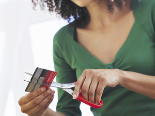 Closeup midsection of a woman cutting credit card against white background