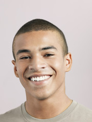 Closeup of young African American man smiling on colored background