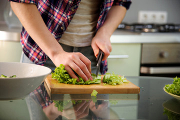 Young woman cuts Chinese cabbage for salad