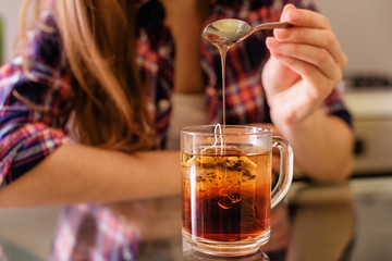 young woman add honey into tea