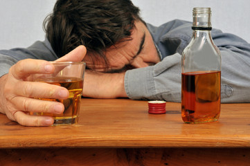 Homme ivre endormi sur une table avec un verre de whisky en main