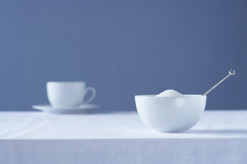 Bowl of sugar on table tea cup in background