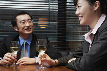 Happy businessman and businesswoman holding wineglasses at cafe table