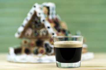 Glass of Dark Coffee in front of Gingerbread House