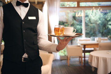 Waiter serving tea at restaurant, close up view