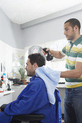 Young hairdresser preparing man for haircut in barber shop