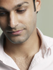 Fototapeta premium Closeup of young man looking down on colored background
