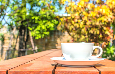white cup of coffee on wooden table in garden cafe