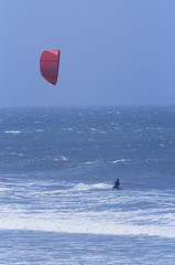 Distance shot of a silhouette person kitesurfing in the sea