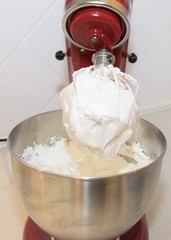 closeup  of whipped egg white on the beater of an stand mixer