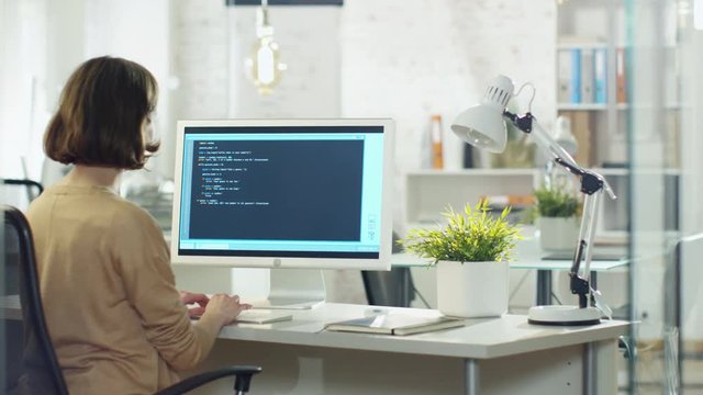 Young Creative Woman Developer Writes Code on Her Desktop Computer. She Sits in Her Modern developer Office. Shot on RED Cinema Camera in 4K (UHD).
